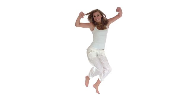 A happy woman is jumping with joy, wearing casual white pants and a tank top. She looks energetic and excited against a white background. This video can be used to represent happiness, enthusiasm, positive emotions, or a carefree lifestyle. It is perfect for advertisements, motivational materials, or wellness campaigns.