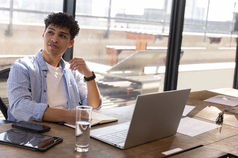 Young professional working at modern rooftop office desk with laptop and tablet