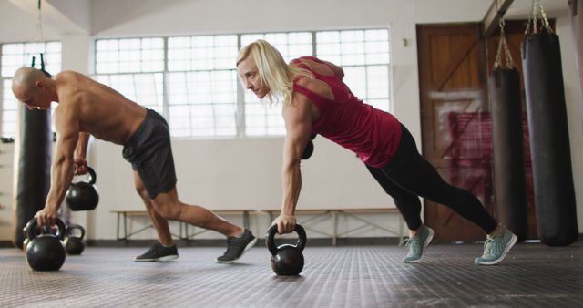 Fit caucasian woman and man working out with kettle bells at the gym. sports, training and fitness concept