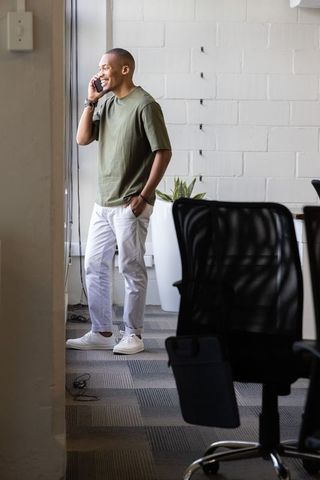 African american man talking on smartphone by window in modern coworking office