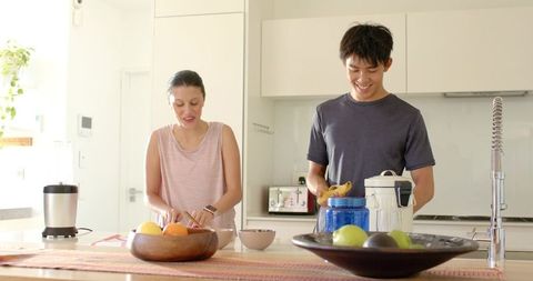 Multicultural couple preparing bright healthy breakfast together in modern minimalist kitchen