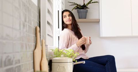 Woman Relaxing in Modern Kitchen by Window