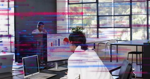 Female analyst reviewing financial charts on large monitor in modern open-plan office