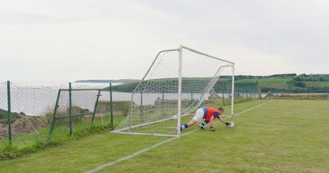 Teenage Soccer Goalkeeper Diving on Outdoor Grass Field