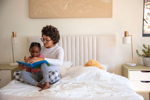 Mother and daughter bonding by reading in cozy bedroom