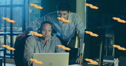 Two coworkers reviewing laptop while mentoring with headset and orange wrench stickers
