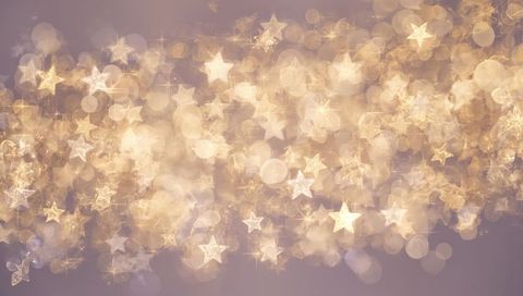Shimmering golden star bokeh creating soft luminous holiday background with sparkling orbs