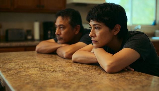Couple leaning on kitchen countertop gazing thoughtfully out window daylight mood