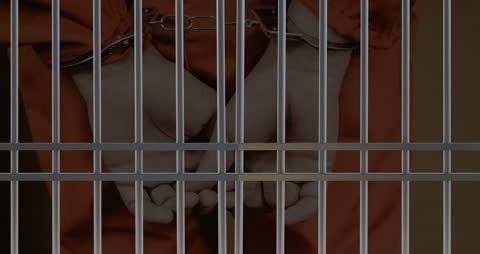 Man in Handcuffs in Prison Behind Bars
