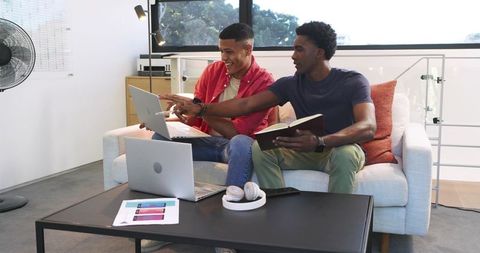 Colleagues collaborating in modern workspace with laptops