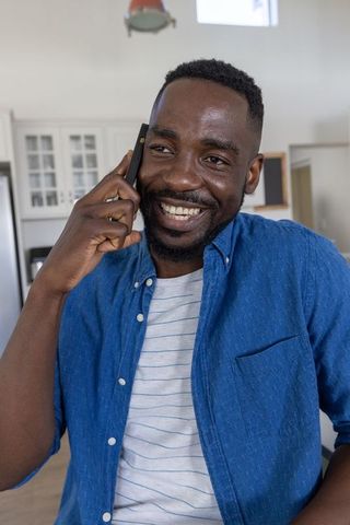 Cheerful Man Conversing on Smartphone in Bright Kitchen Setting