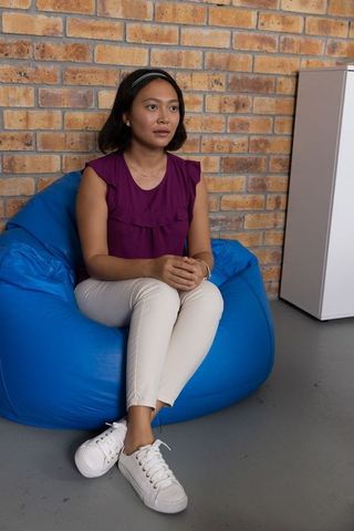 Relaxed asian woman enjoying comfort on blue bean bag chair