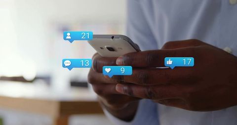 Holding smartphone displaying social media notification badges for likes followers