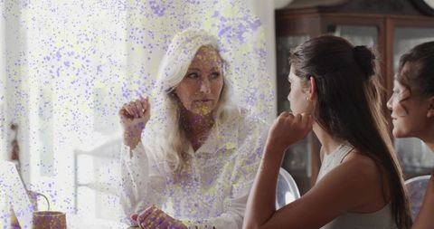 Senior woman leading family conversation at dining table with young women listening