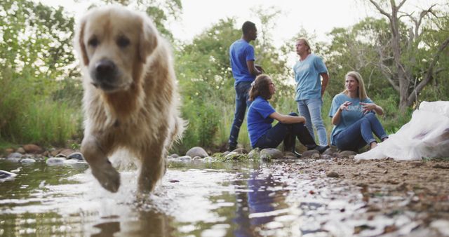 A multi-ethnic group of happy conservation volunteers cleaning up a river in the countryside, picking up rubbish with a dog. Ecology and social responsibility in a rural environment.