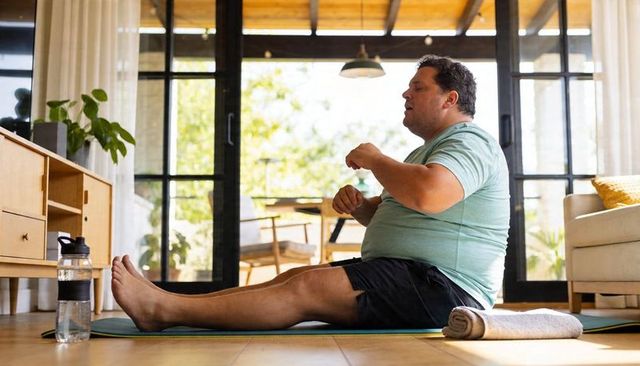 Man stretching on mat in sunlit living room for home workout and gentle fitness routine