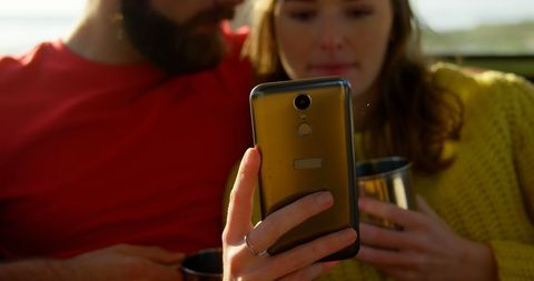 Close-up of couple enjoying phone on sunny day