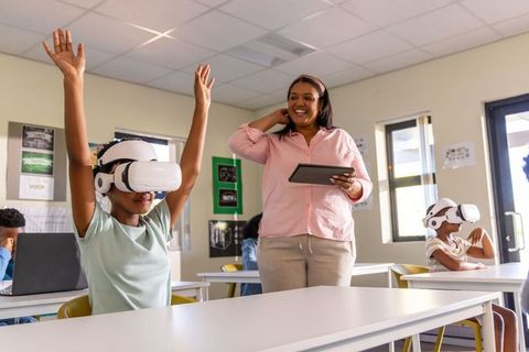 African american teacher leading vr lesson with students using virtual reality headsets