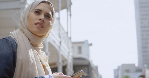 Muslim Woman in Hijab Exploring Urban Cityscape with Smartphone