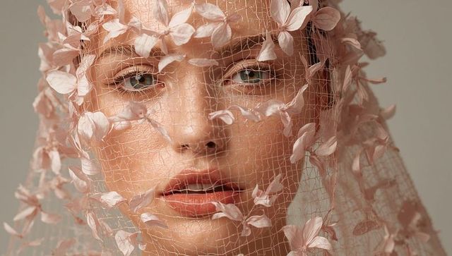 Gazing model veiled in pastel petals capturing ethereal beauty close-up portrait