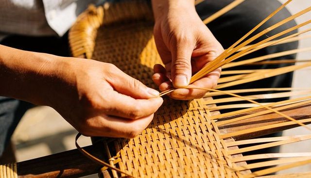 Weaving rattan chair seat handcrafting herringbone cane pattern with artisan hands