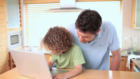 Father and Son Exploring Laptop Together in Bright Kitchen