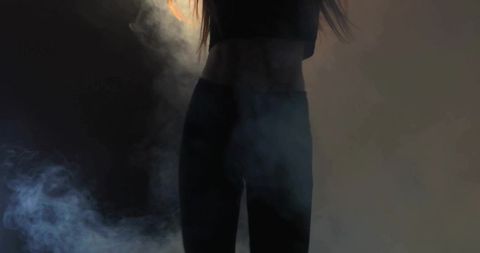 Backlit female torso posing in black crop top and leggings with smoky studio mood