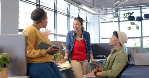 Diverse coworkers collaborating in bright modern office with tablet and headphones