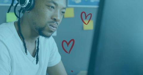 Focused man in t-shirt wearing headphones and working at computer monitor