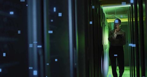 IT Technician Inspecting Server Racks in Green-Lit Data Center with Tablet