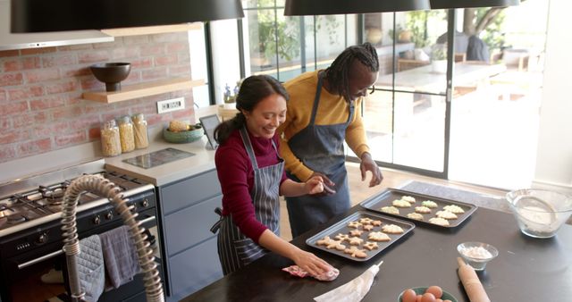 Couple enjoying baking gingerbread cookies together in a contemporary kitchen. Suitable for concepts about family activities, bonding, home baking, modern lifestyle, and domestic living. Can be used for promoting recipes, home cooking products, and kitchenware.