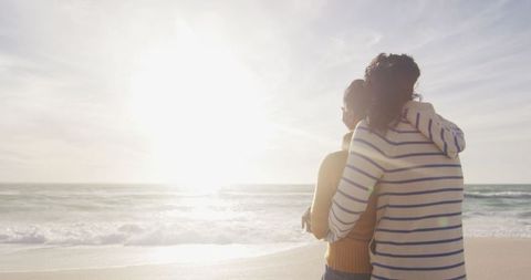 Romantic hispanic couple embracing on beach at sunset
