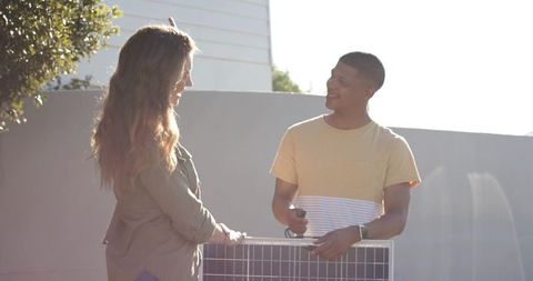 Holding and connecting solar panel at home, couple installing renewable energy system