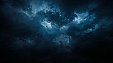 Dramatic negative energy swirling storm clouds in moody night sky