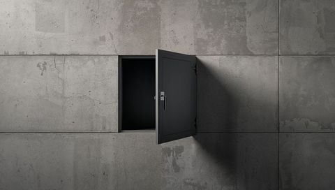 Open metal access hatch swinging on concrete wall exposing dark cavity and dramatic shadow