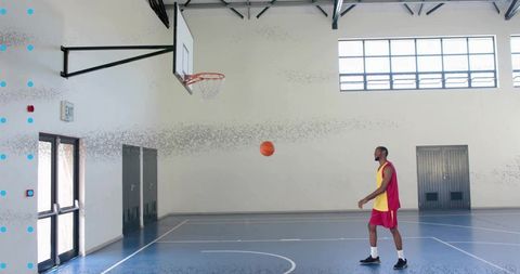 Male Athlete Dribbling Basketball in Indoor Gym With Hoop