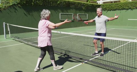 Senior Couple Enjoying Tennis Game and Embracing Celebration