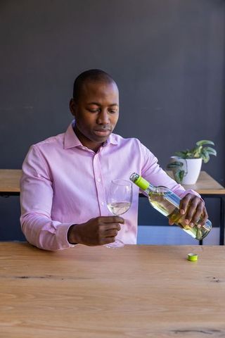 Elegant man pouring white wine in modern interior