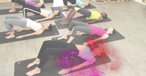 Group pilates yoga holding glute bridge pose on mats in bright studio for core strength