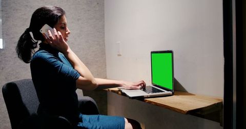 Businesswoman Multitasking with Mobile Phone and Laptop