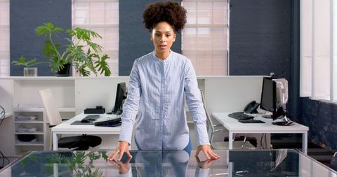 Confident Businesswoman Standing at Desk in Modern Office