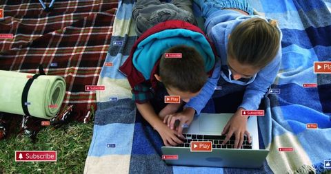 Children using laptop checking subscribe icons picnic outdoors