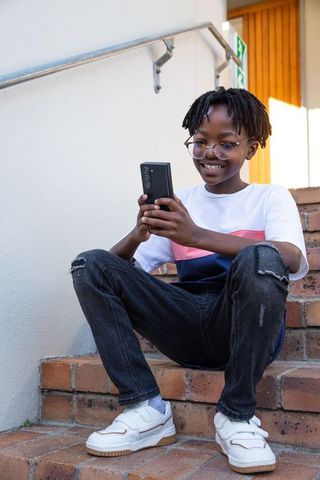 Teenager Joyfully Engaging with Smartphone on Urban Brick Steps