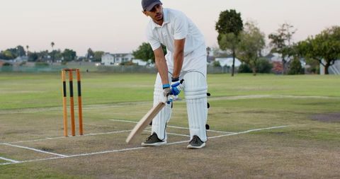 Indian cricketer standing at crease holding bat in white kit during twilight practice