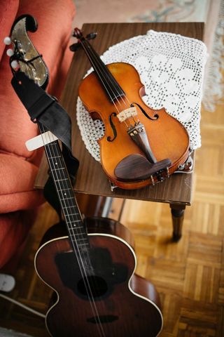 Acoustic guitar and violin on wooden table doily