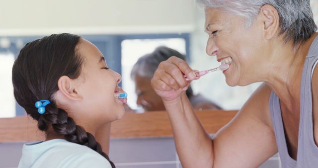 Grandmother and grandchild enjoying a morning routine together in bathroom. Promotes messages of family bonding and oral hygiene. Suitable for family-themed advertisements, dental care promotions, and healthy lifestyle campaigns.
