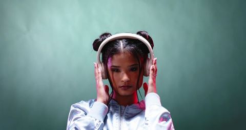 Stylish woman in neon lit studio listening to music