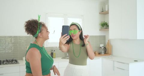 Taking green-themed selfie in bright kitchen celebrating friendship and festive style