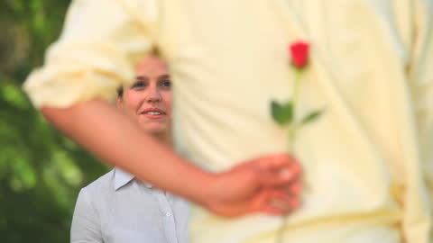 Man Surprising Girlfriend with Rose in Sunny Park