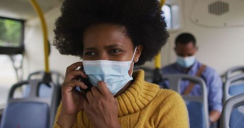 Woman in face mask talking on mobile phone in public transport
